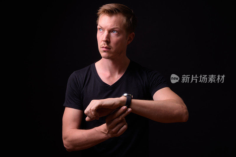 Studio Portrait Of Man Against Black Background Using Smart Watch